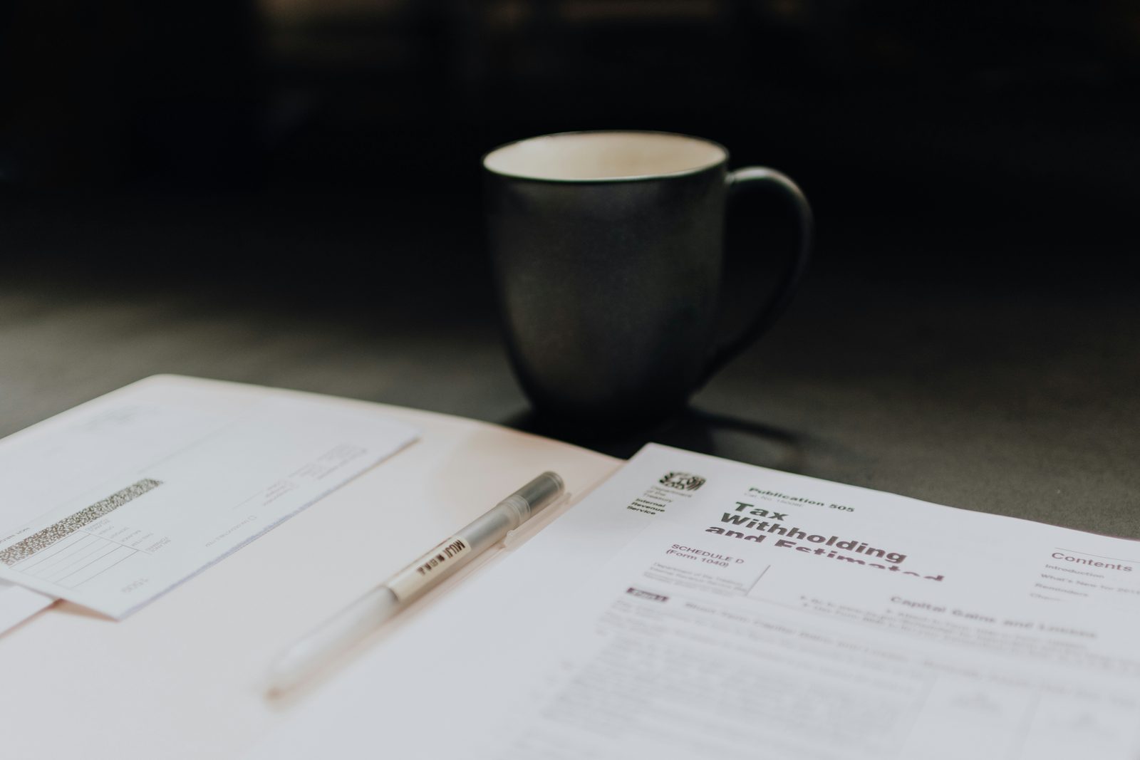 A coffee mug beside scattered paperwork in soft light